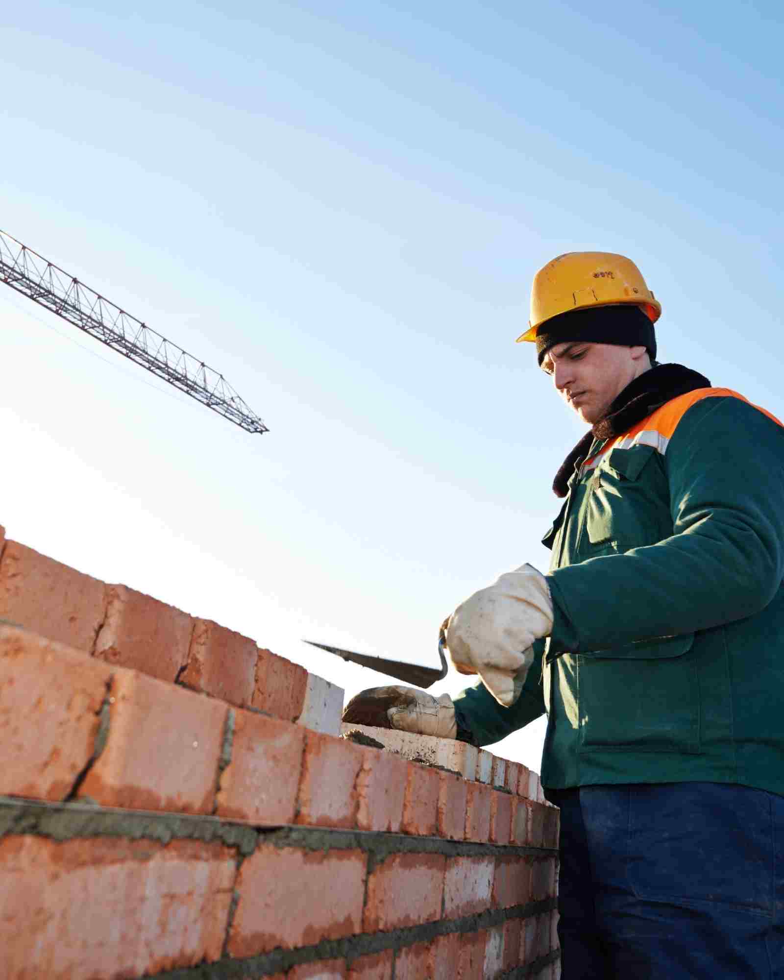 Maçon construisant un mur en parpaing sur un chantier français