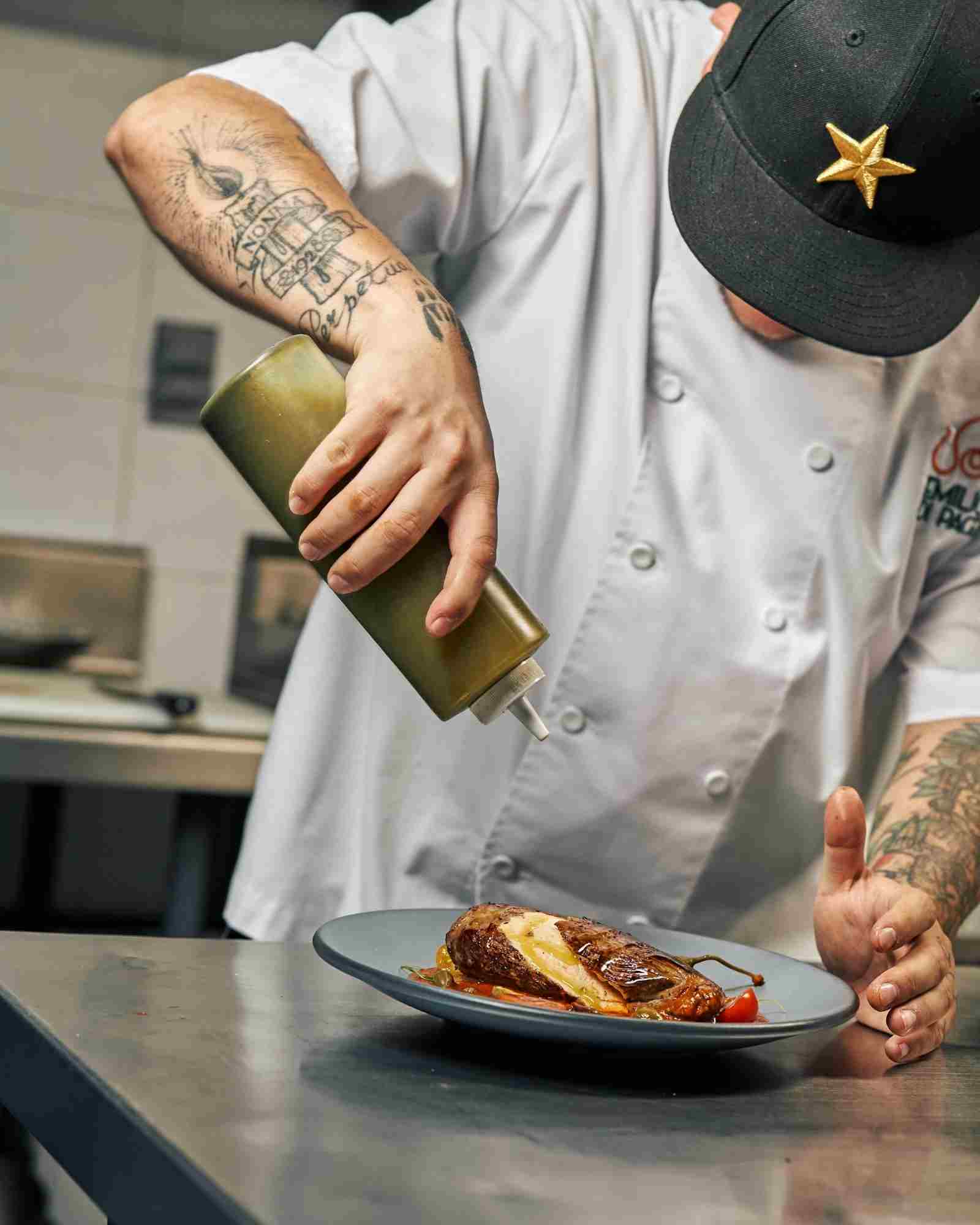 French chef plating a dish in a professional kitchen brigade