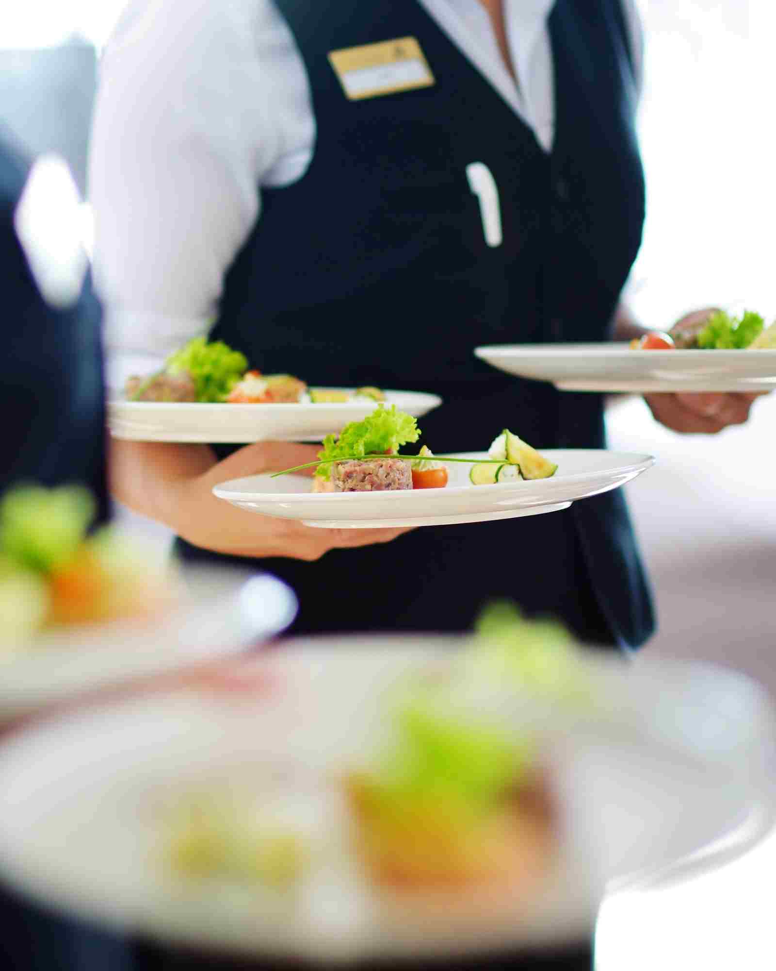 French waiter carrying plates in a restaurant dining room